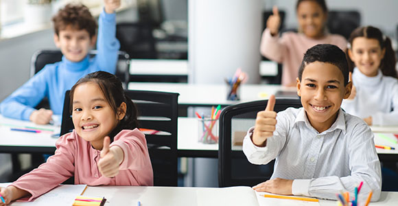 Four students in class giving thumbs-up.