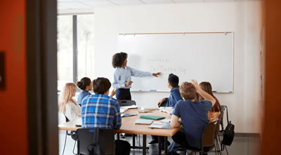 Teacher at whiteboard teaching seated students math