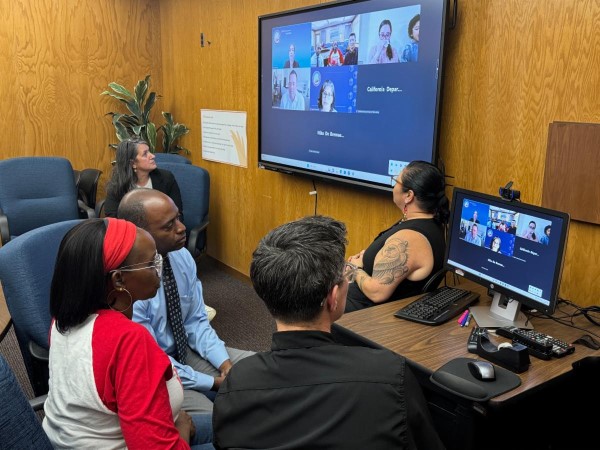 State Superintendent Tony Thurmond in a room with other people participating in a virtual meeting.
