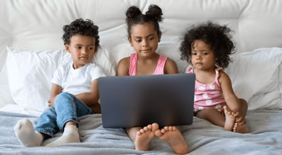 Three girls of different ages viewing a laptop screen together